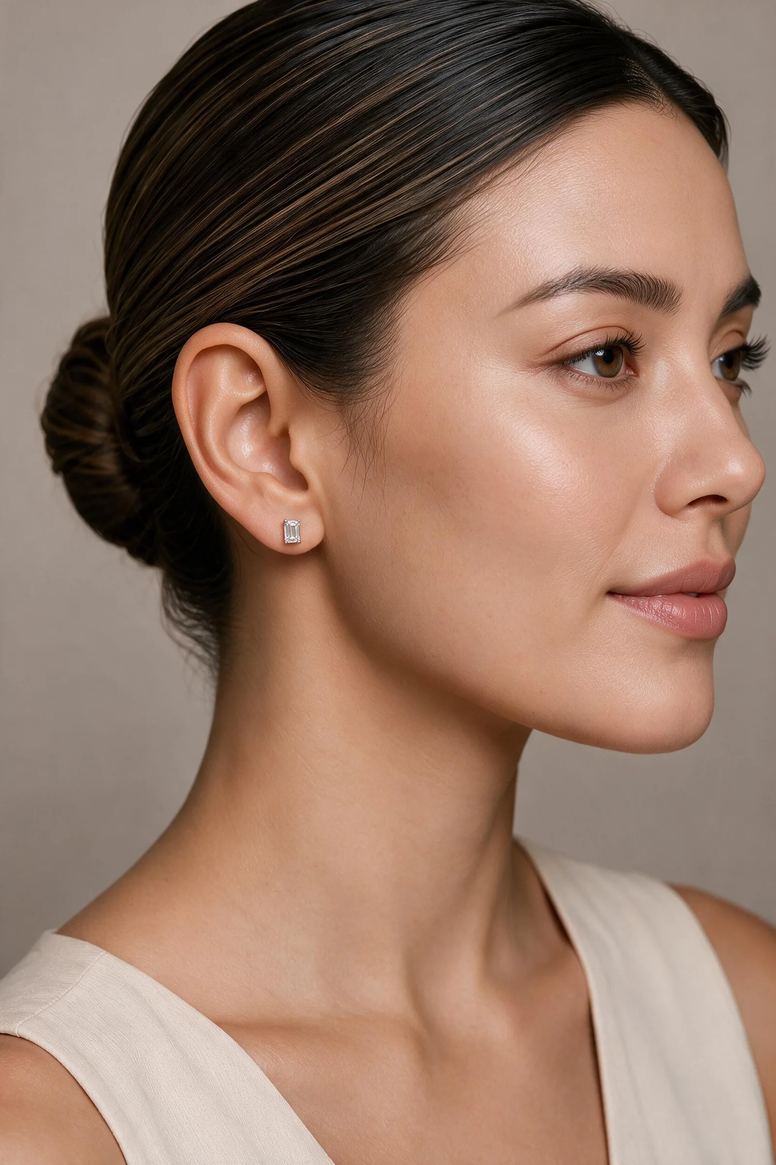 An emerald-cut diamond stud earring worn on the ear
